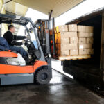 Electric forklift in warehouse loading cardboard boxes